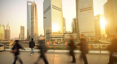 People walking on a busy boardwalk with an urban skyline in the background