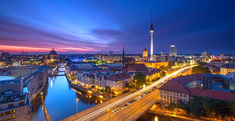 Berlin skyline panorama showing the TV Tower at Alexanderplatz, cathedral and traffic against a blue purple sunset