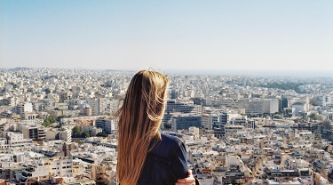 Une entrepreneure regardant l’horizon, au-dessus des toits d’une grande ville.