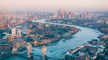 Aerial view of London, England, featuring buildings, residential areas, a river and a bridge.