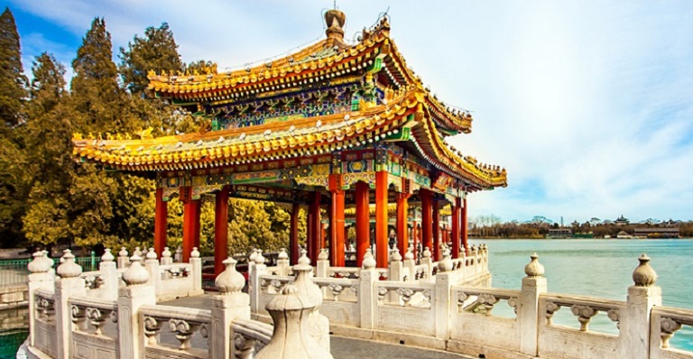 A colourful Asian pagoda sits at the edge of a lake.