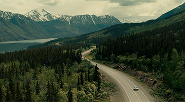 A road cutting through Indigenous land of trees and mountains. Indigenous companies can partner with the government on projects to reach net zero targets