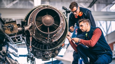 Two engineers working on a jet engine of a small airplane.