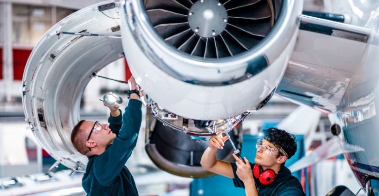 Deux ingénieurs de maintenance inspectent un moteur d’avion dans un hangar d’entretien.