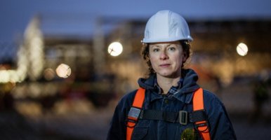 Une travailleuse canadienne de la construction, en équipement de sécurité, pose sur un chantier avec une expression neutre.