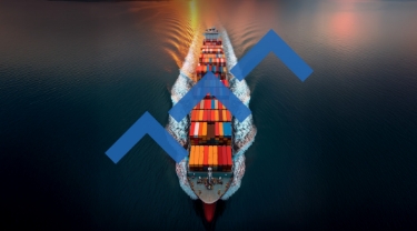 Aerial view of a large cargo ship loaded with colourful shipping containers sailing across the ocean at sunset, overlaid with upward-pointing blue arrows suggesting growth or progress
