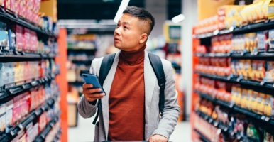 Un bel homme asiatique recherche des produits d'épicerie dans la liste sur son téléphone.
