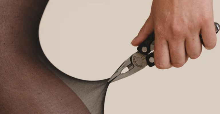 A person wearing SRTX tights using long nose pliers to pull on tights demonstrating the products strength.