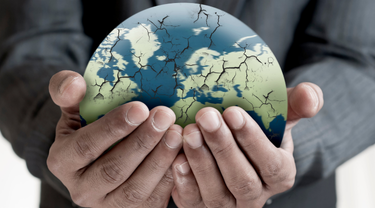 Closeup of man’s hands holding cracked globe.