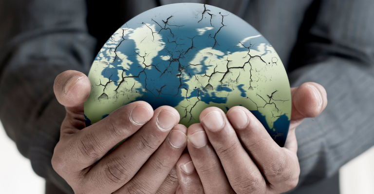Gros plan sur les mains d’un homme tenant un globe terrestre fissuré