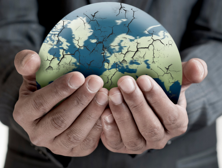 Closeup of man’s hands holding cracked globe.