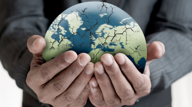 Closeup of man’s hands holding cracked globe.