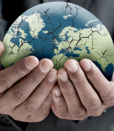 Closeup of man’s hands holding cracked globe.