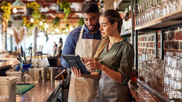 Restauranteurs discuss deliveries while standing behind their beautiful bar.