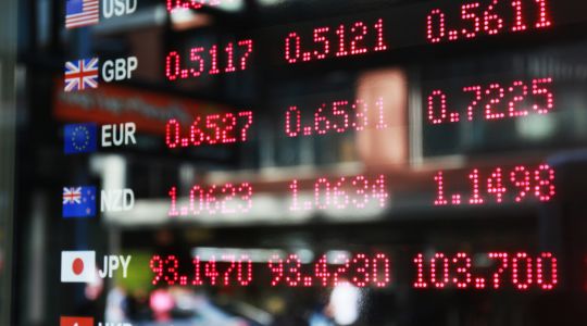 Digital currency exchange board displaying current rates for multiple international currencies including USD, GBP, EUR, NZD, JPY and HKD.