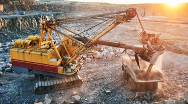 Mining excavator loading granite into dump at quarry.