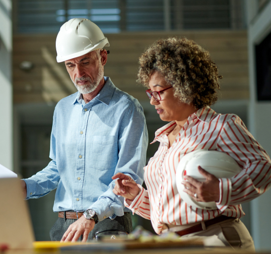 Project managers cooperating while working on blueprints at a construction building