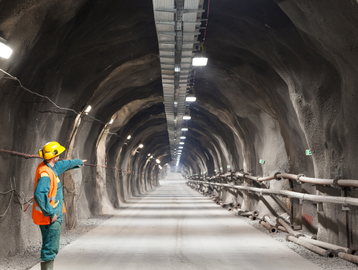 Professional underground worker pointing down a tunnel.