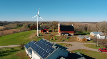 Eocycle’s high-performance wind turbine stands on a rural farm, where solar panels are installed on the farmhouse roof.