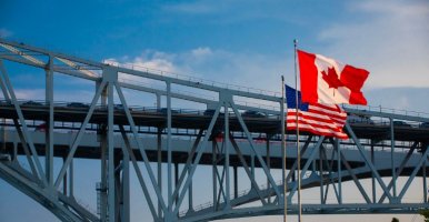 Drapeaux américain et canadien au premier plan du pont Blue Water reliant l’Ontario et le Michigan
