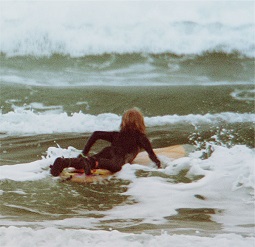 Young boy paddling out on surfboard