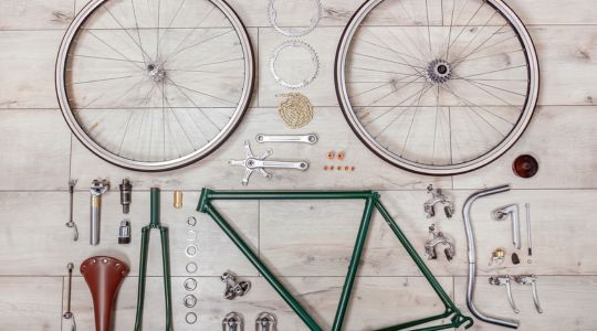 Un cadre de vélo et ses composants posés sur des planches de bois.