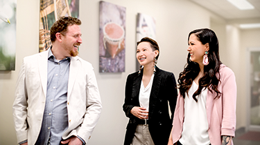 Three individuals discussing and smiling while standing up