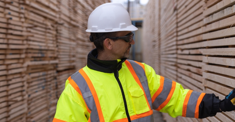 Al Balisky, président et chef de la direction de Meadow Lake Tribal Industrial Investments, inspecte des piles de produits de bois d'œuvre finis.