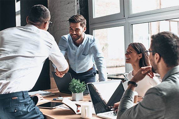 A group of people having a discussion. Young modern men in smart casual wear shaking hands and smiling while working in an office.