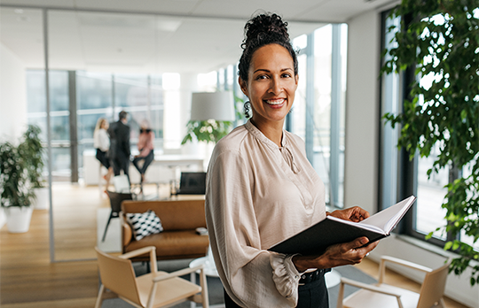 Smiling business professional holding a book open in an office