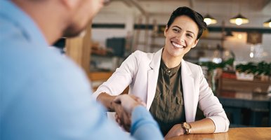 Une femme confiante et souriante serre la main d’une autre personne