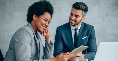 Une femme noire évalue le rapport de son collègue sur sa tablette.