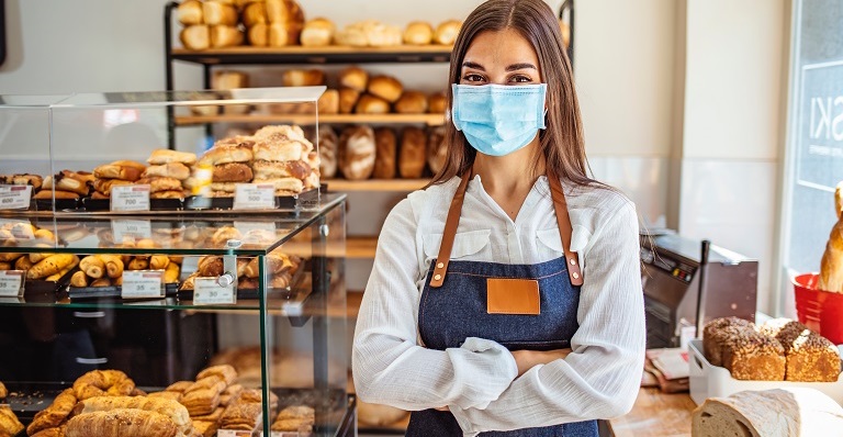 Le propriétaire d’un café consulte en souriant l’Outil de suivi sur son ordinateur portable