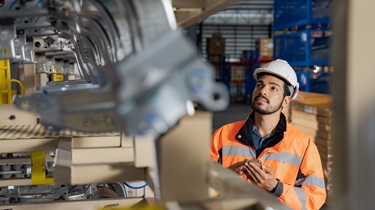 Male engineer works on metal car parts in plant.