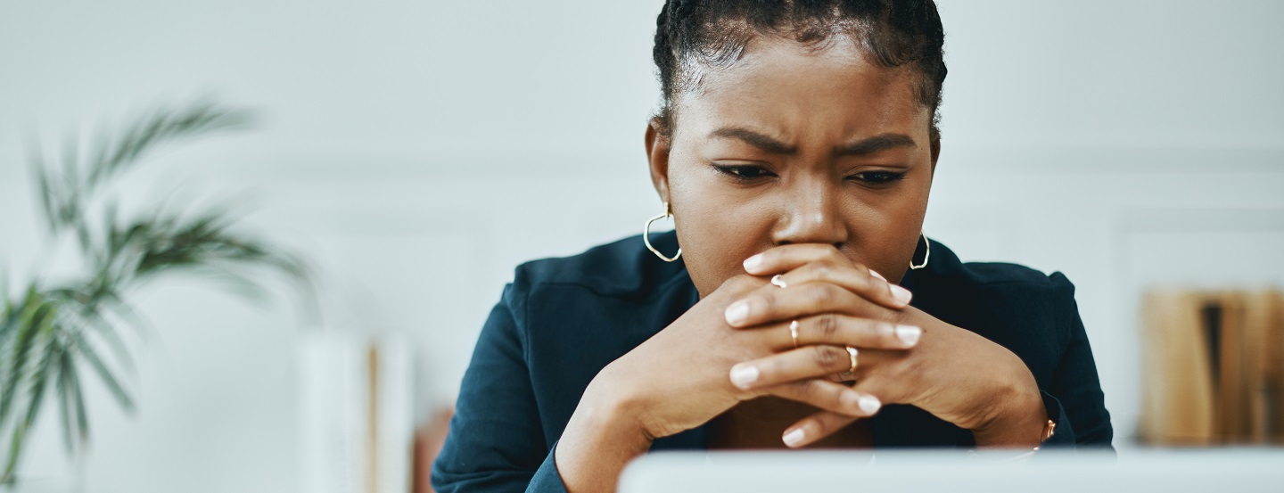 Une femme semble confuse alors qu'elle lit un document sur son ordinateur au bureau.