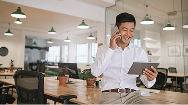 Businessman talking to an export advisor on the phone and looking at company information on his tablet