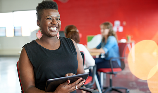 Confident black woman entrepreneur working on a tablet in an office space