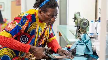 Designer dressed in colourful jacket cuts fabric