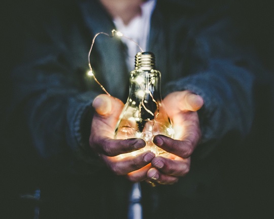 Hands holding a glowing lightbulb 