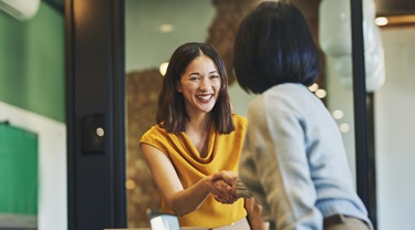 Asian business woman shaking hands with a client.