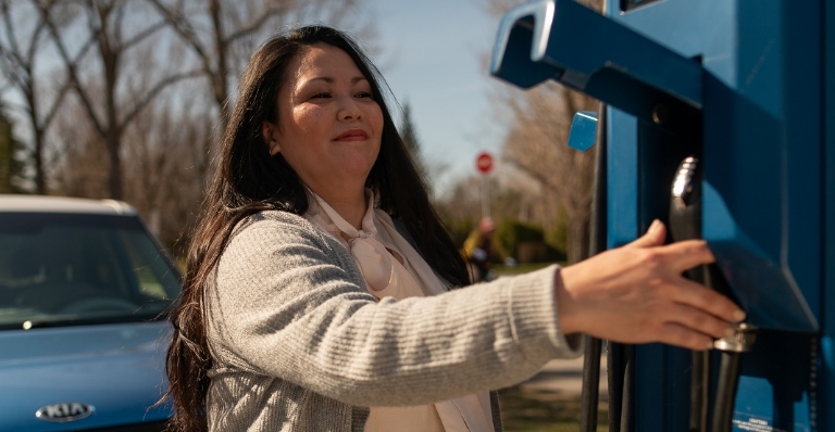 Femme branchant son véhicule électrique.