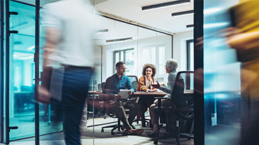 Business professionals meeting in a glass-walled office conference room