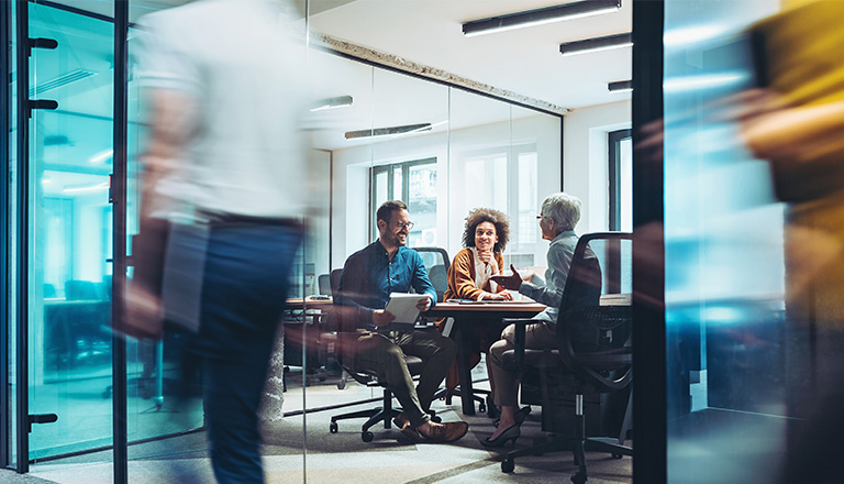 Business professionals meeting in a glass-walled office conference room