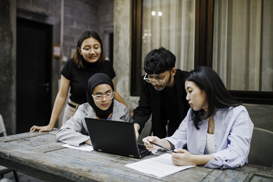 A group of people working together on a laptop in the Indo-Pacific