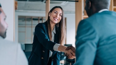 Female trade expert welcomes business owners into her office.