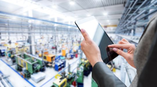 Les mains d’une femme d’affaires tapant sur une tablette dans une usine.