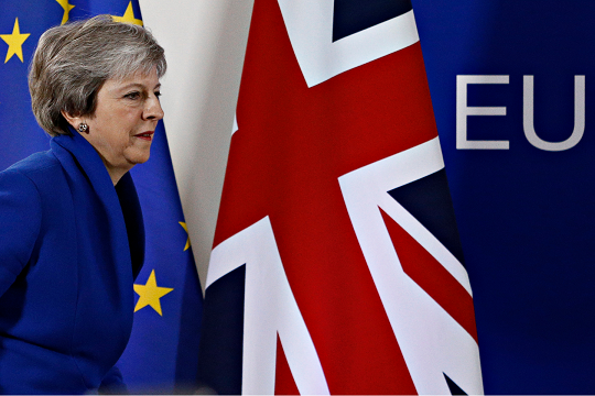 British Prime Minister Theresa May walks by a row of flags in the lead up to Brexit vote.