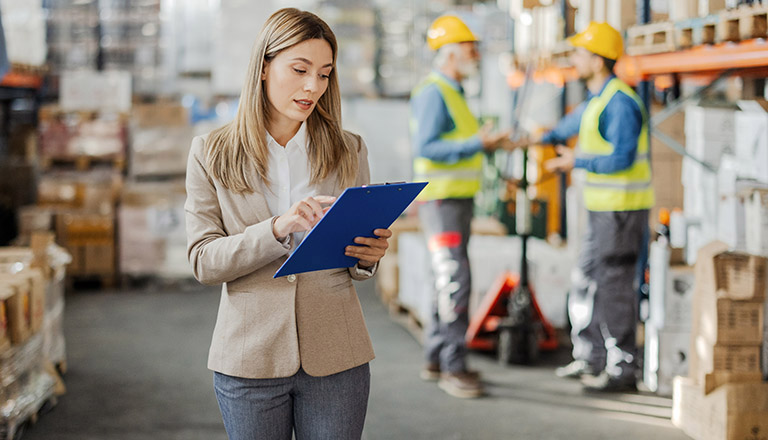 Gestionnaire d'entrepôt féminin vérifiant les produits dans une allée d'entrepôt.