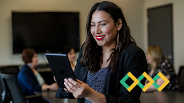 A smiling woman with dark hair looks at a digital tablet