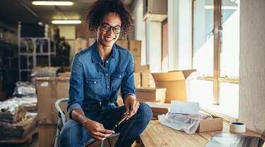 Women holding pen in warehouse while smiling.